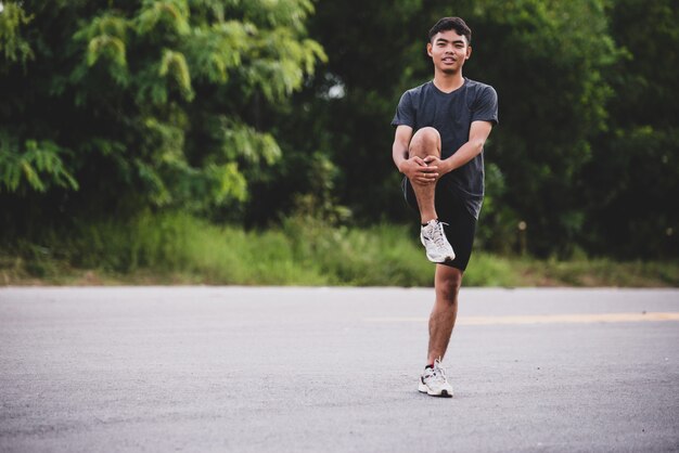 Corredor masculino haciendo ejercicios de estiramiento, preparándose para el entrenamiento