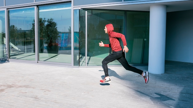 Corredor masculino joven de la aptitud que corre fuera del edificio