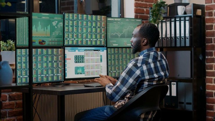 Foto gratuito corredor masculino que utiliza estadísticas de intercambio de divisas en múltiples monitores, trabajando con gráficos de mercado y ventas de acciones en tiempo real. participación en los beneficios de los fondos de cobertura para comprar y vender dinero. disparo de trípode.