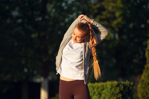 Corredor de sexo femenino joven, atleta está trotando en la calle de la ciudad bajo el sol.