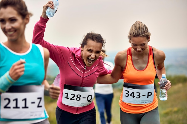 Corredores alegres divirtiéndose mientras participan en una carrera en la naturaleza