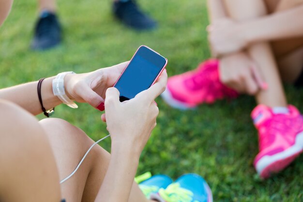 Correr chicas divirtiéndose en el parque con teléfono móvil.