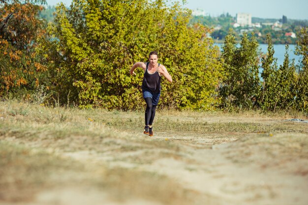 Correr deporte. Hombre corredor corriendo al aire libre en la naturaleza escénica. Ajuste musculoso atleta masculino sendero de entrenamiento para correr maratón. Hombre atlético en forma deportiva trabajando en ropa de compresión en sprint