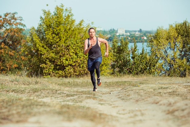 Correr deporte. Hombre corredor corriendo al aire libre en la naturaleza escénica. Ajuste musculoso atleta masculino sendero de entrenamiento para correr maratón. Hombre atlético en forma deportiva trabajando en ropa de compresión en sprint