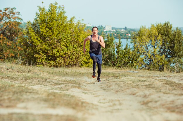 Correr deporte. Hombre corredor corriendo al aire libre en la naturaleza escénica. Ajuste musculoso atleta masculino sendero de entrenamiento para correr maratón.