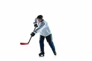 Foto gratuita corriendo. jugador de hockey masculino joven con el palo en la cancha de hielo y fondo blanco. deportista con equipo y casco practicando. concepto de deporte, estilo de vida saludable, movimiento, movimiento, acción.
