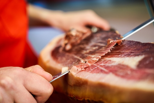 Cortador profesional que talla rebanadas de un jamón serrano entero con hueso