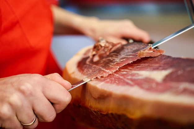 Foto gratuita cortador profesional que talla rebanadas de un jamón serrano entero con hueso