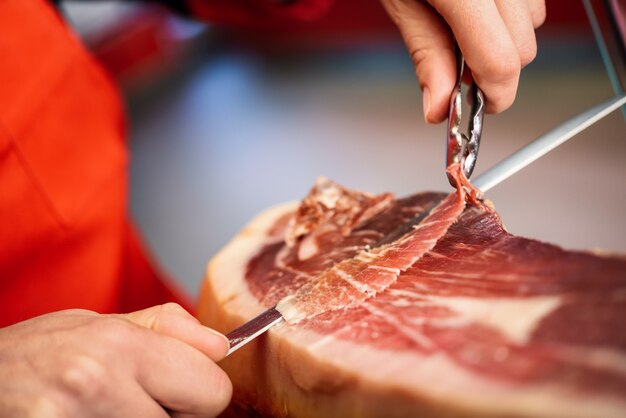 Cortador profesional que talla rebanadas de un jamón serrano entero con hueso