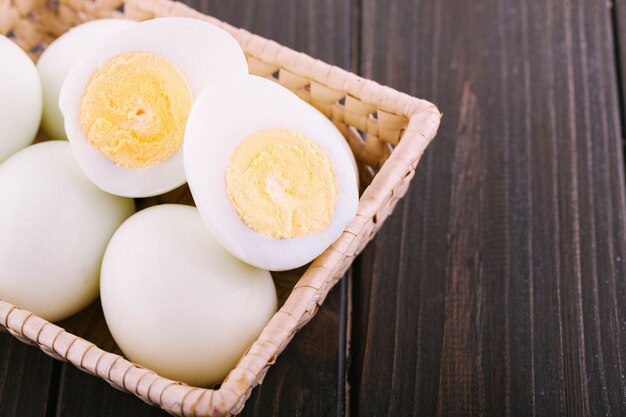 Cortar huevos duros se encuentran en besket de madera en la mesa de comedor oscura