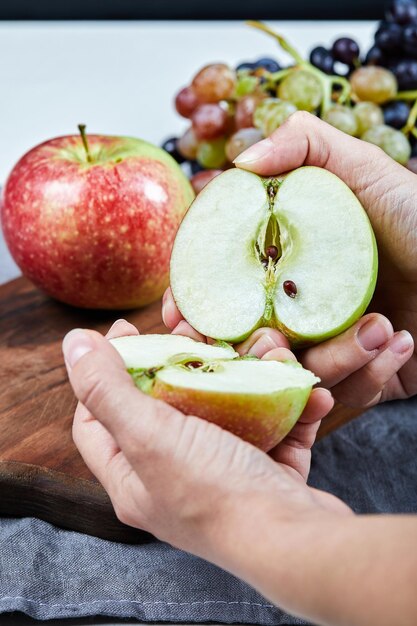 cortar una manzana en dos mitades y un racimo de uvas sobre una tabla de madera.