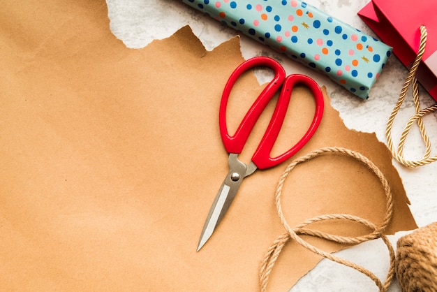 Cortar con tijeras; Cuerda de yute y caja de regalo envuelta sobre papel marrón.