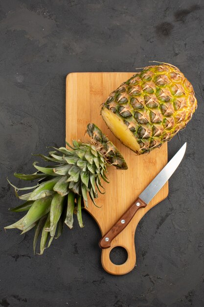 Foto gratuita corte la piña fresca y jugosa en un escritorio de madera y fondo gris