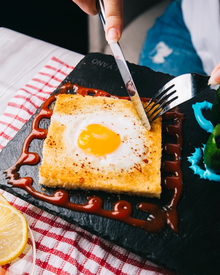 Foto gratuito corte las tostadas con huevo frito con cubiertos.