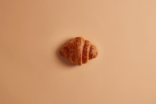 Corteza croissant de mantequilla dulce delicioso para el desayuno sobre fondo marrón. Confitería recién horneada, delicioso postre, comida chatarra. Producto de panadería casera para los golosos. comida francés