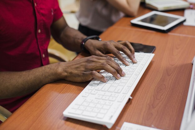 Cosecha hombre negro escribiendo en el teclado