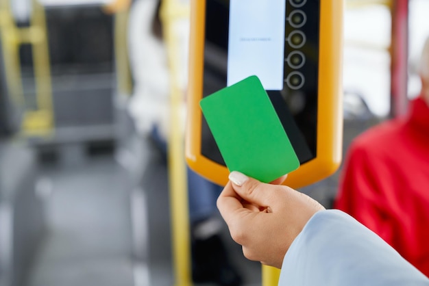 Foto gratuita cosecha de mano femenina usando validador para pago mientras aborda en transporte público cerca de la mano