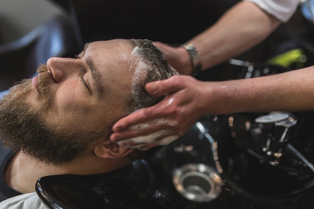 Foto gratuita cosecha de peluquería lavando el cabello del cliente