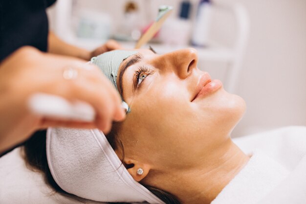 Cosmetóloga aplicando una máscara en la cara del cliente en un salón de belleza