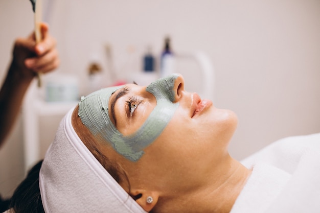 Cosmetóloga aplicando una máscara en la cara del cliente en un salón de belleza