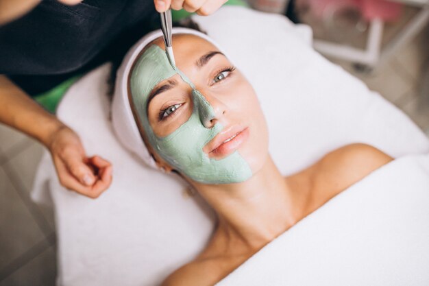 Cosmetóloga aplicando una máscara en la cara del cliente en un salón de belleza