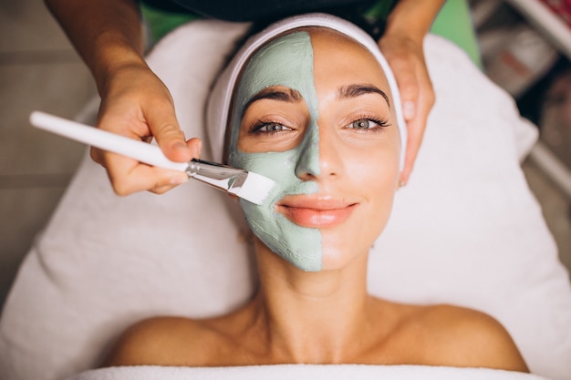 Foto gratuita cosmetóloga aplicando una máscara en la cara del cliente en un salón de belleza