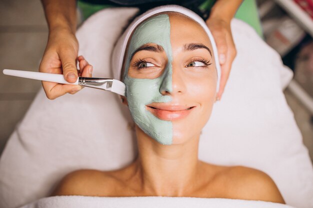 Cosmetóloga aplicando una máscara en la cara del cliente en un salón de belleza