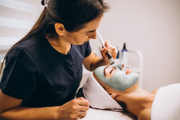 Foto gratuita cosmetóloga aplicando una máscara en la cara del cliente en un salón de belleza