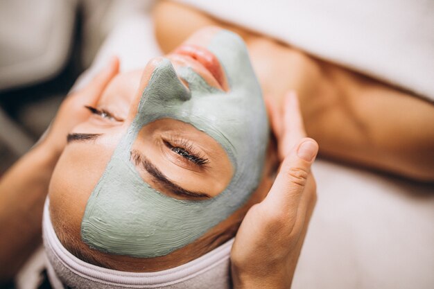 Cosmetóloga aplicando una máscara en la cara del cliente en un salón de belleza