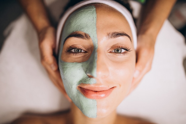 Cosmetóloga aplicando una máscara en la cara del cliente en un salón de belleza