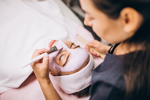 Foto gratuita cosmetóloga aplicando una máscara en la cara del cliente en un salón de belleza