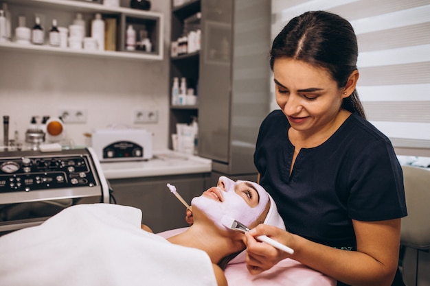 Foto gratuita cosmetóloga aplicando una máscara en la cara del cliente en un salón de belleza