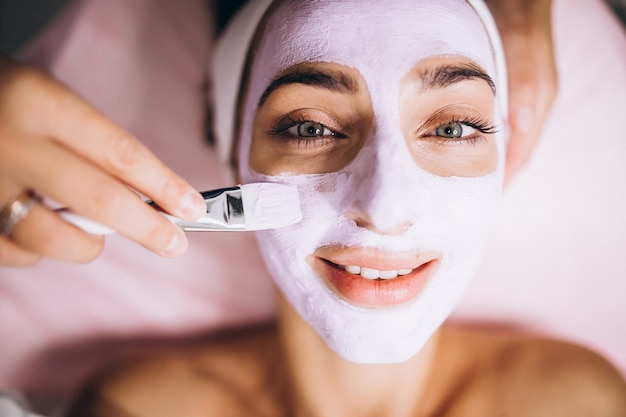 Cosmetóloga aplicando una máscara en la cara del cliente en un salón de belleza