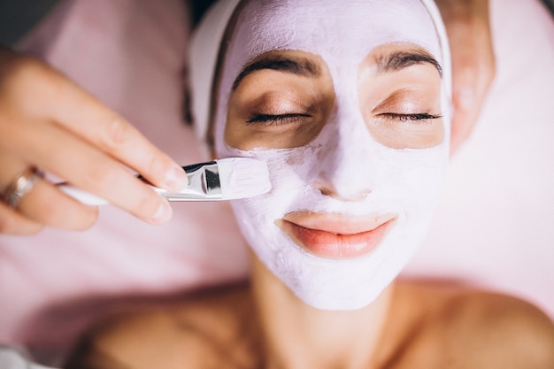 Foto gratuita cosmetóloga aplicando una máscara en la cara del cliente en un salón de belleza