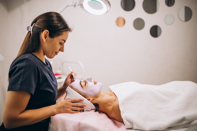 Foto gratuita cosmetóloga aplicando una máscara en la cara del cliente en un salón de belleza