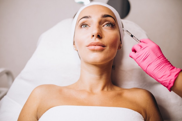 Foto gratuita cosmetóloga haciendo inyecciones en la cara de una mujer en un salón de belleza