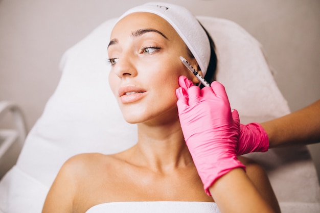 Cosmetóloga haciendo inyecciones en la cara de una mujer en un salón de belleza
