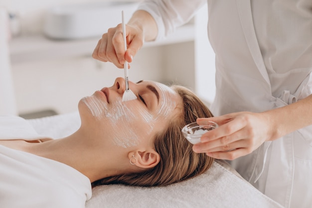 Cosmetóloga haciendo tratamiento facial y aplicando mascarilla