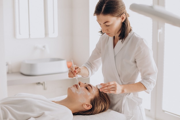 Cosmetóloga haciendo tratamiento facial y aplicando mascarilla