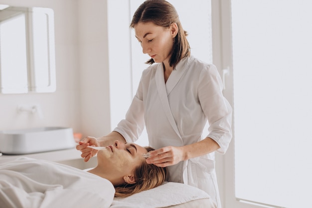 Cosmetóloga haciendo tratamiento facial y aplicando mascarilla