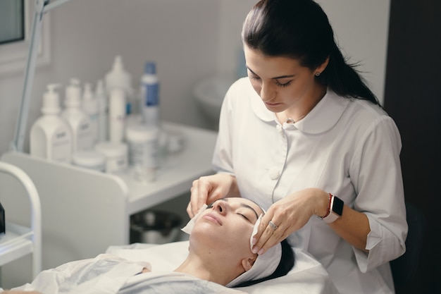 Cosmetóloga haciendo tratamiento facial a una bella mujer