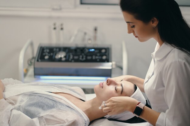 Cosmetóloga haciendo tratamiento facial a una bella mujer