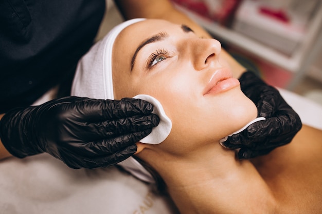 Foto gratuita cosmetóloga limpiando la cara de una mujer en un salón de belleza