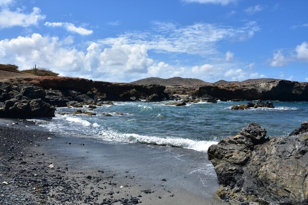 Costa accidentada en la playa de piedra de arena negra