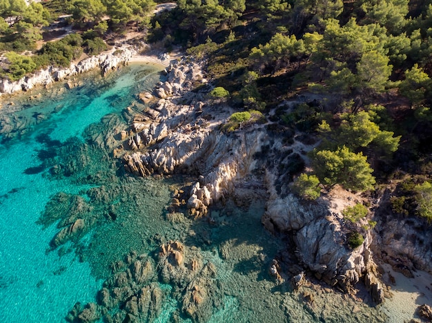 Costa del mar Egeo con agua azul transparente, vegetación alrededor, rocas, arbustos y árboles, vista desde el zumbido, Grecia