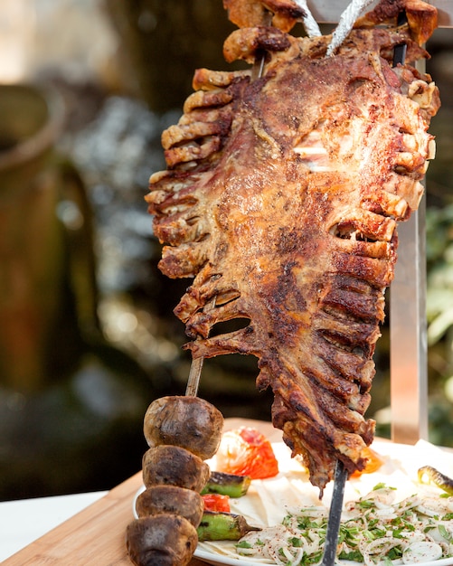 Costillas de cordero enteras kebab y papas a la parrilla en brochetas de acero