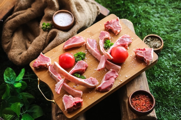 Costillas de cordero saladas preparadas para cocinar tomates, pimientos verdes, vista lateral