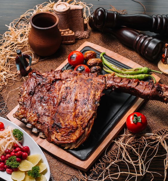 Foto gratuita costillas a la plancha sobre la plancha de madera tomate pimiento patata vista lateral