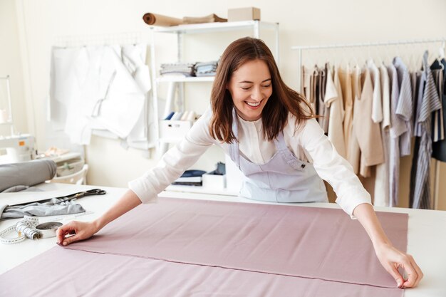 Costurera mujer extendiendo telas en taller