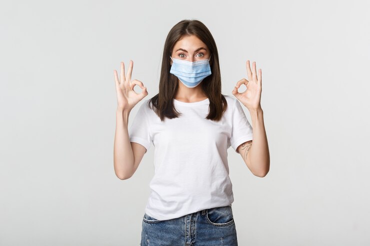 Foto gratuito covid-19, concepto de salud y distanciamiento social. emocionada niña bonita sonriente en máscara médica mostrando gesto bien satisfecho.